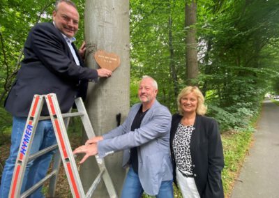 Gravierte Holzherzen zieren Bäume an Kreisstraße